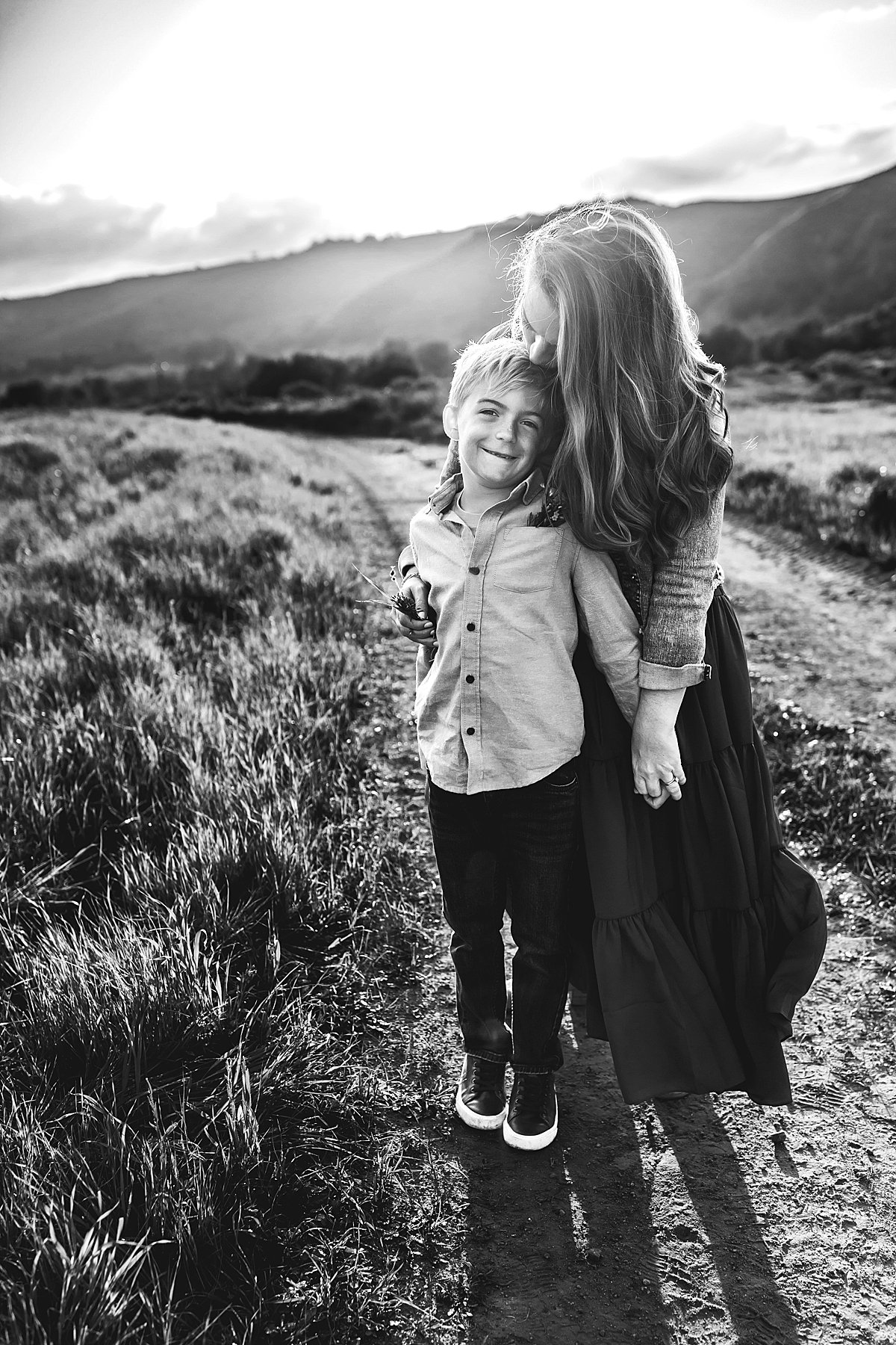  mother and son holding one another on trail path for sunset field family session 