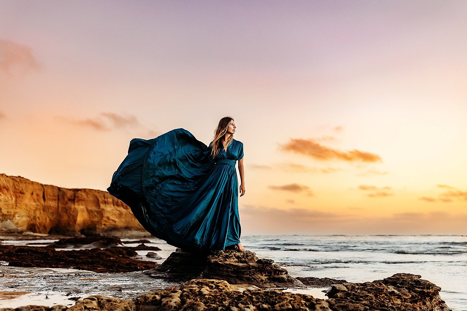  senior wearing long blue dress on sunset cliffs during blue hour 
