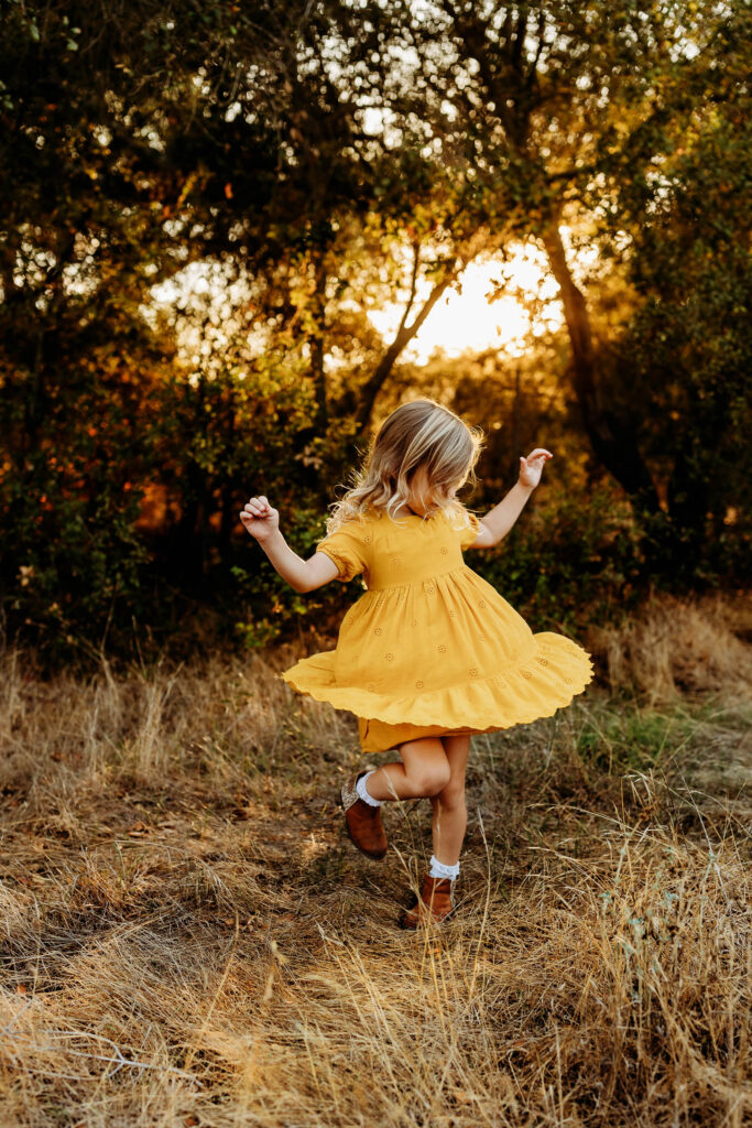 Little girl twirling in a field in Estes Park.