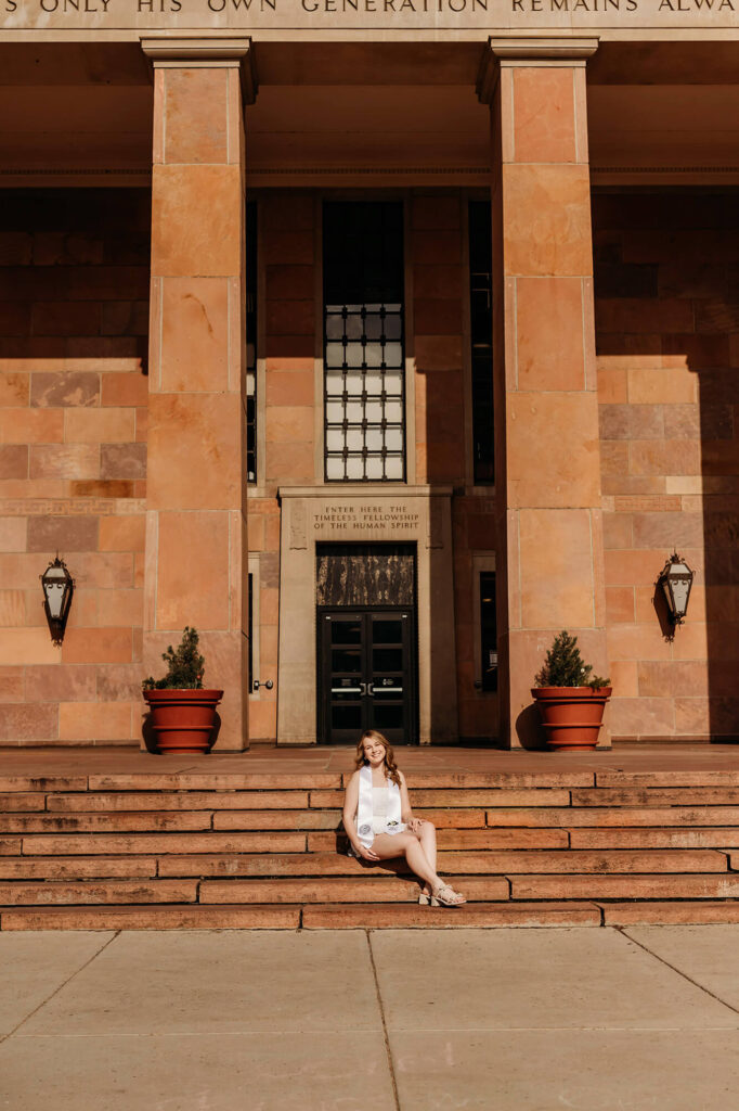 CU Boulder grad sitting on the steps of Norlin Library. 