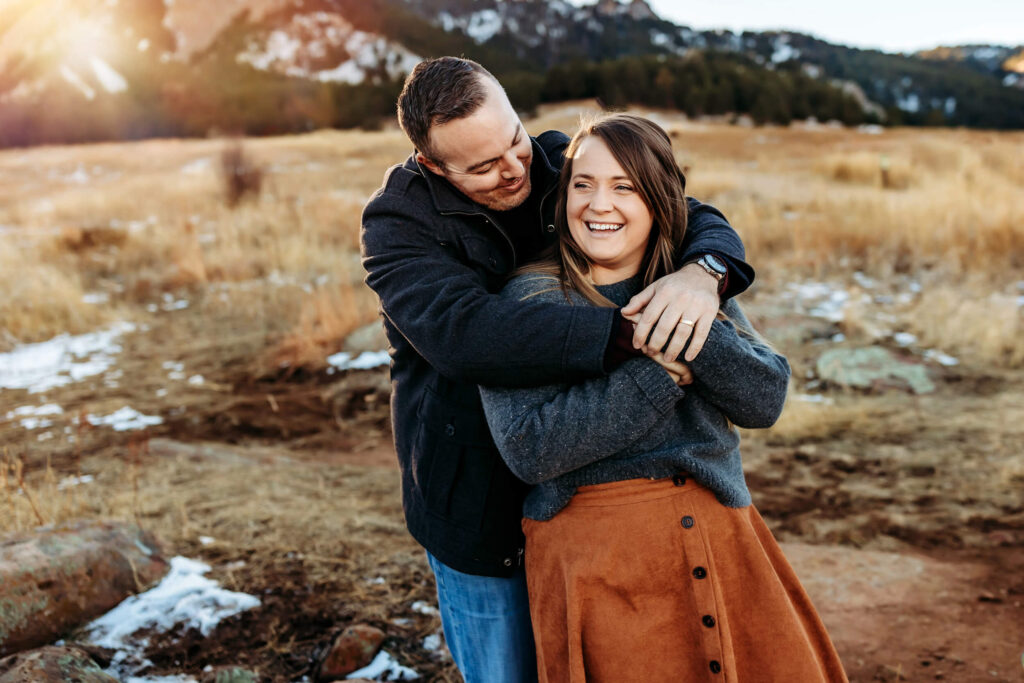 Husband and wife hugging and laughing together in the Boudler sunset. 