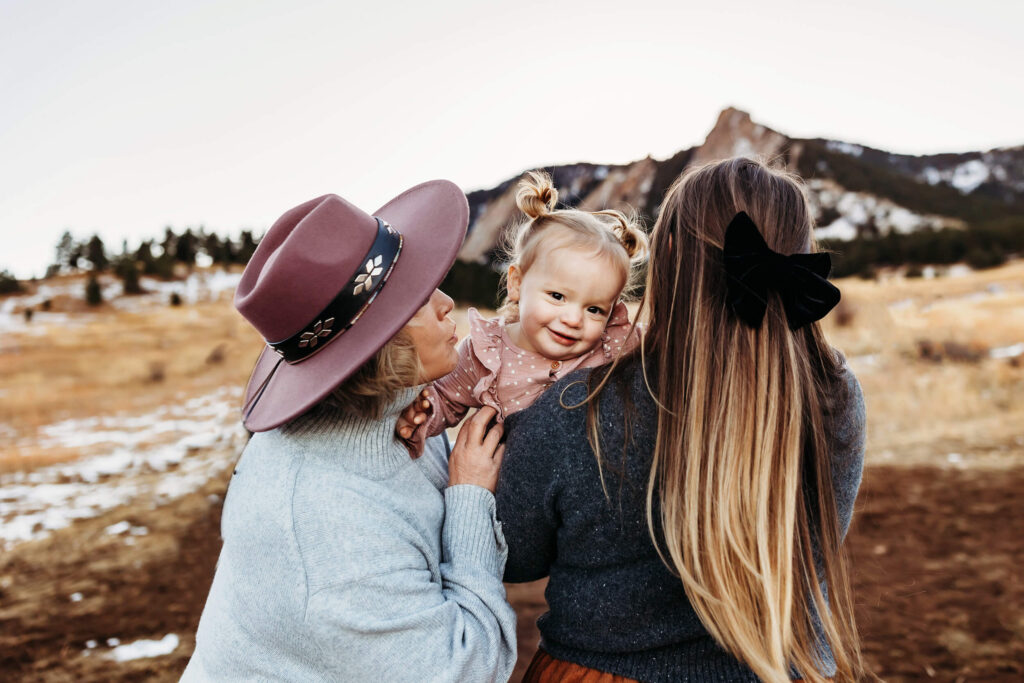 Grandma kissing toddler granddaughter while mom holds her in Boulder, Colorado. 