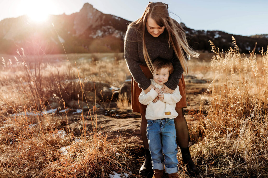 Mom and toddler son standing together for their boulder family photographer in the sunset. 