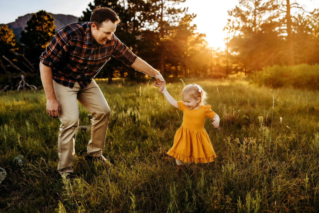 Dad twirling toddler daughter in the Boulder sunset. 